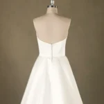 Back view of a satin wedding dress on a mannequin, featuring a simple button closure and a full skirt, ideal for bridal shops.