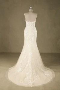 Back view of an elegant, fitted lace wedding dress featuring a backless design with intricate floral patterns on a mannequin.
