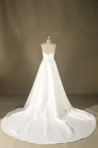 Back view of a strapless white bridal gown on a mannequin, featuring a long flowing train. Ideal for upscale weddings.