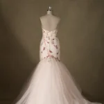 Back view of a strapless mermaid wedding dress on mannequin, featuring floral embroidery and a voluminous tulle skirt.