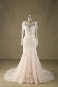 Ivory bridal gown with lace applique, long sleeves, and illusion neckline on mannequin against neutral background.