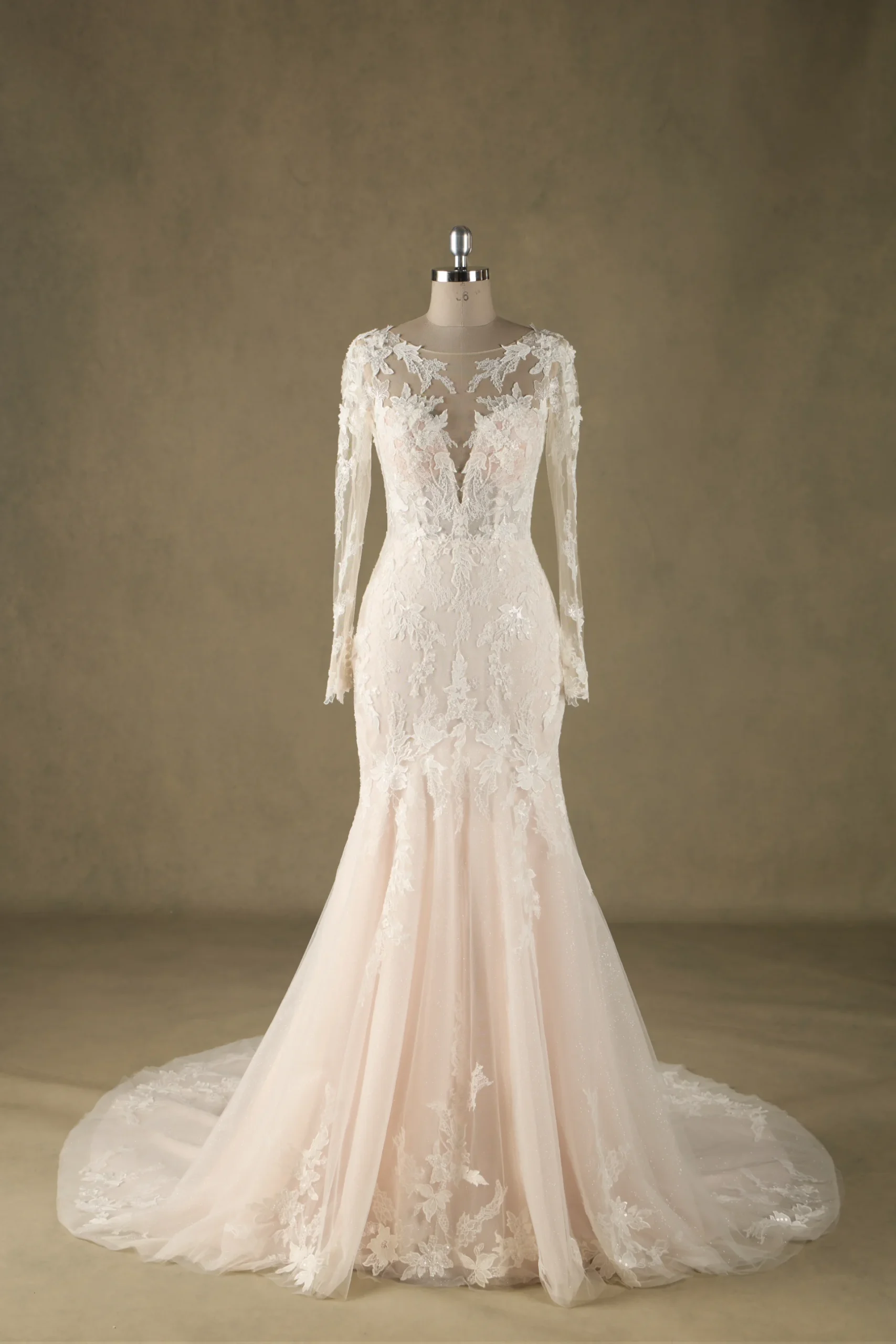 Ivory bridal gown with lace applique, long sleeves, and illusion neckline on mannequin against neutral background.