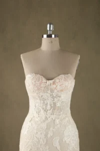 A close-up view of a lace strapless wedding dress on a mannequin, showcasing intricate floral lace details.