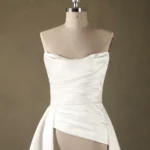 A strapless bridal gown with elegant pleats shown on a mannequin with a neutral background, suitable for wedding boutiques.