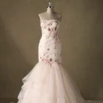 Elegant strapless mermaid wedding gown adorned with floral embroidery, displayed on a mannequin against a neutral backdrop.