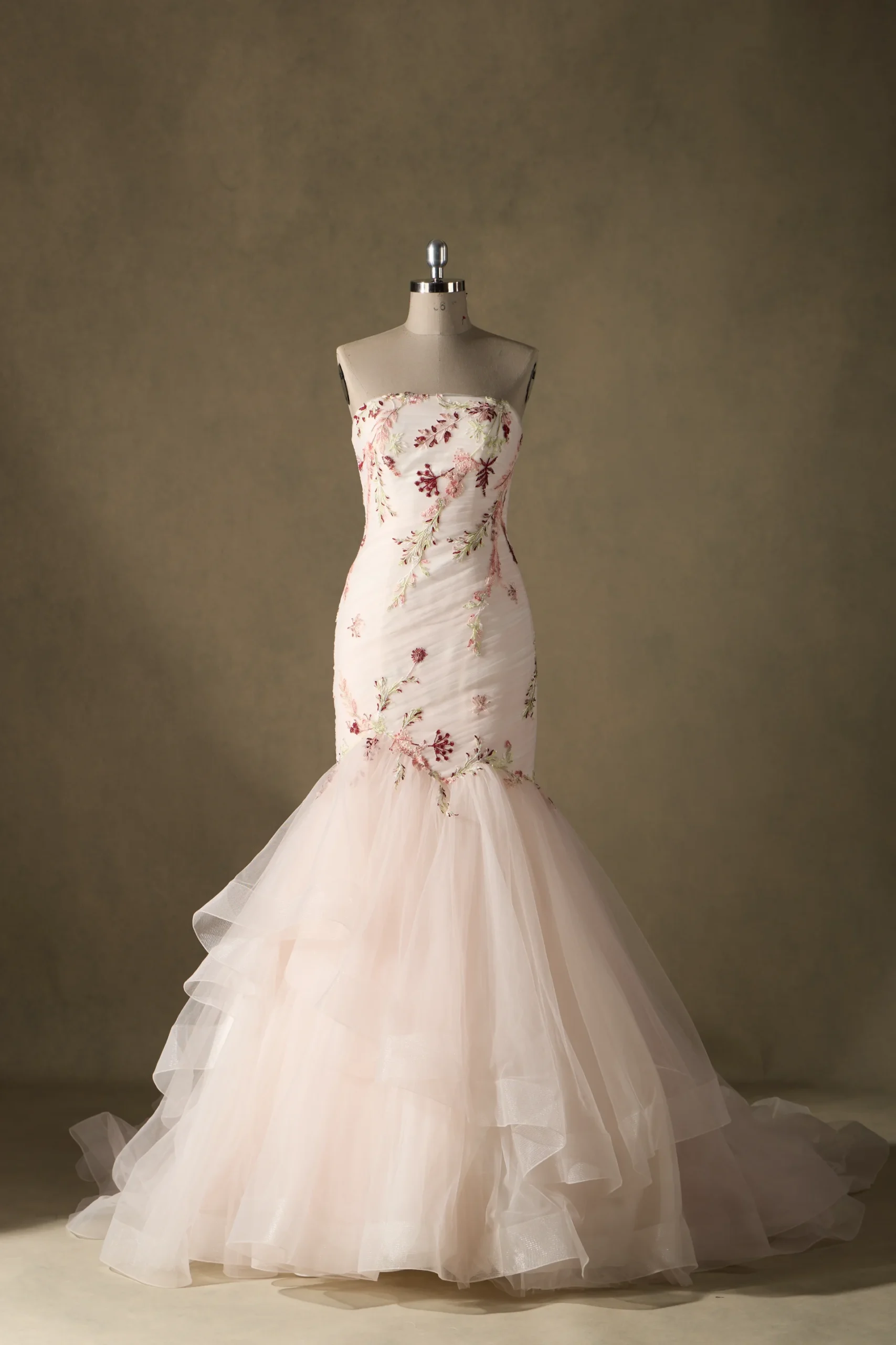 Elegant strapless mermaid wedding gown adorned with floral embroidery, displayed on a mannequin against a neutral backdrop.