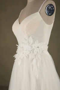Close-up of a wedding dress featuring a floral applique design with sequins on a mannequin.