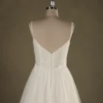 Back view of an elegant backless wedding dress with delicate straps on a mannequin, showcasing intricate detailing and flowing skirt.