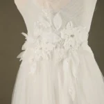 Close-up of an elegant bridal gown featuring delicate floral embellishments and intricate beading on a flowing white fabric.