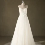 White bridal gown displayed on a mannequin against a neutral background, featuring delicate floral details and flowing tulle skirt.