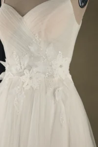 Close-up of a wedding dress featuring intricate floral embroidery and delicate sequins on a mannequin.